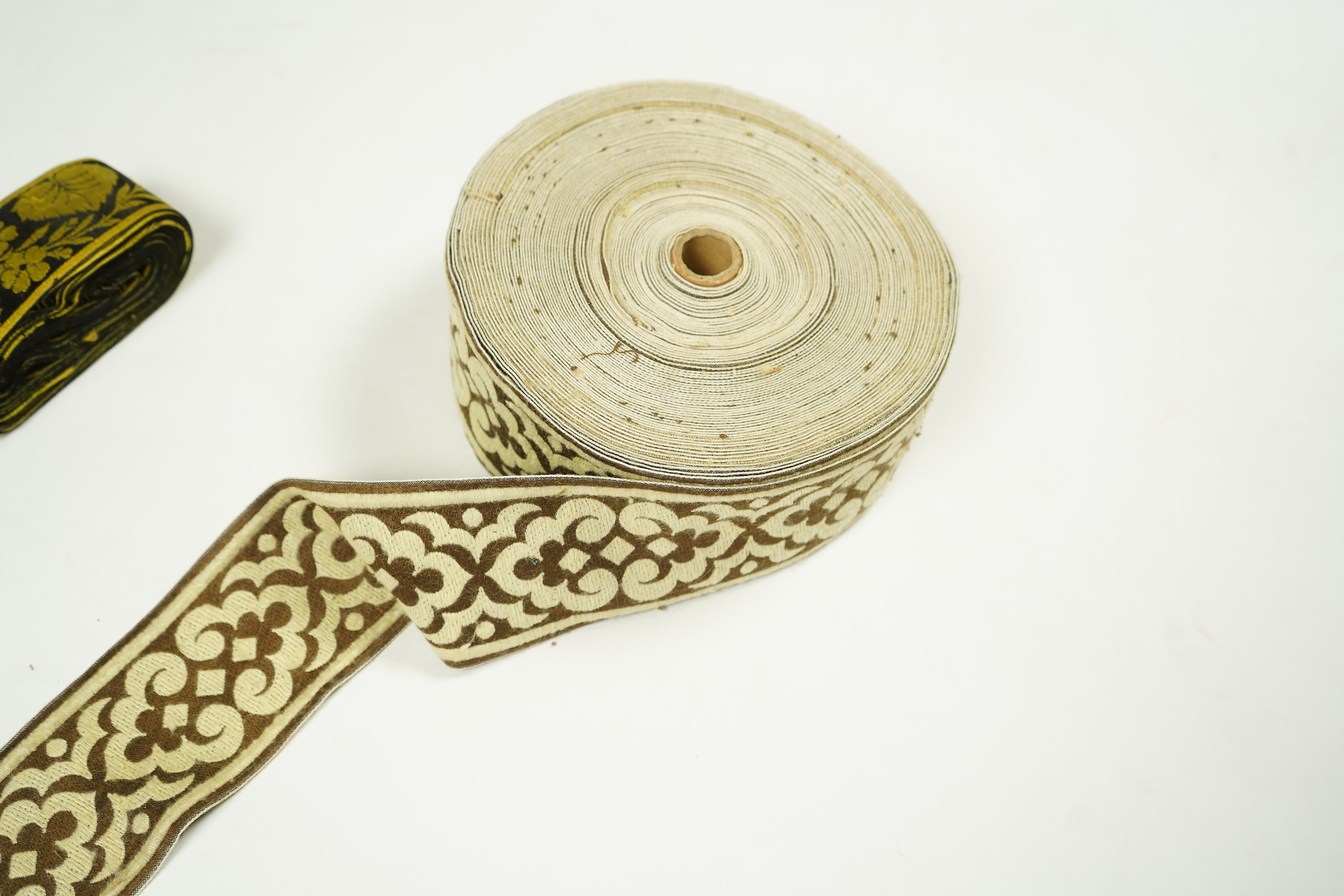 Three long lengths of late 19th century silk woven braiding. One woven in gold, turquoise and maroon silk, possibly for ecclesiastic use, in Christopher Dresser ‘style’ motifs, another in gold and black silk thread in a